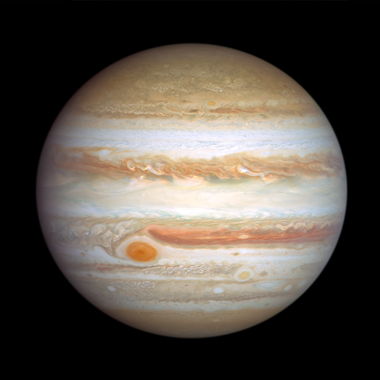 Hubble Space Telescope image of Jupiter taken on January 5, 2024. Jupiter is banded in stripes of brownish orange, light gray, soft yellow, and shades of cream, punctuated with many large storms and small white clouds. The largest storm, the Great Red Spot, is the most prominent feature in the left bottom third of this view. To its lower right is a smaller reddish anticyclone, Red Spot Jr.