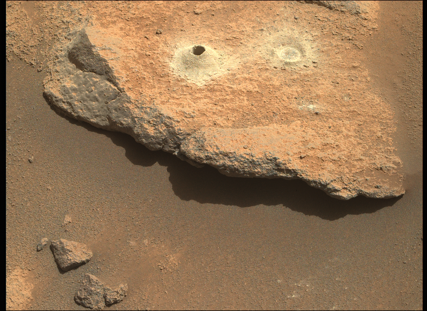 Image taken was taken by the Mars Perseverance rover after collecting the rock sample 6 at Robine. The image shows a rock with a drillhole and abrasion.