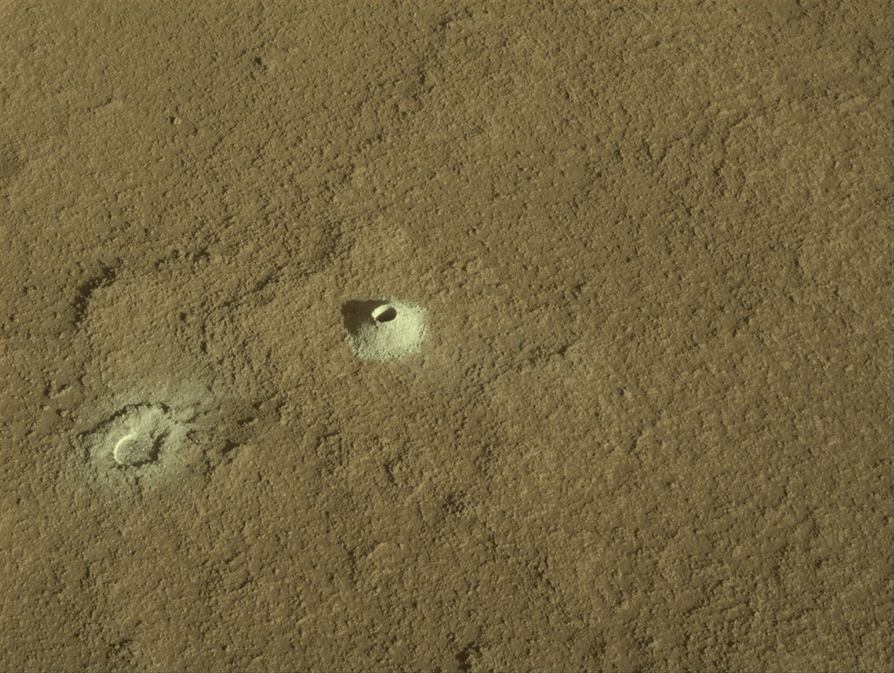 Image taken was taken by the Mars Perseverance rover after collecting the rock sample 23 at Lefroy Bay. There is a drill hole in the center of the martian soil with an abrasion patch at the bottom left.