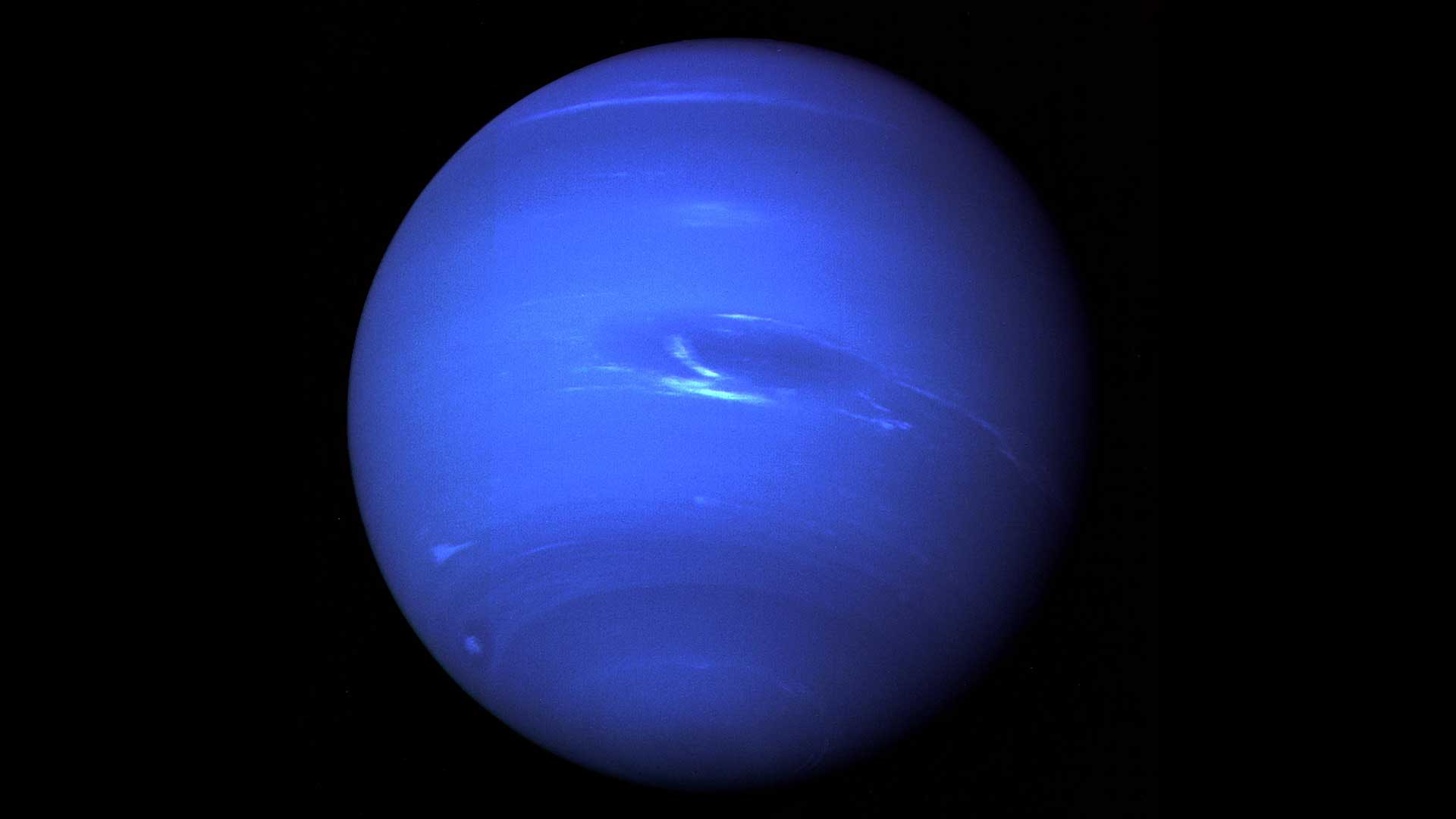 Neptune is a deep blue with darker bands, and white cloud bands in this image from the Voyager 2 spacecraft.