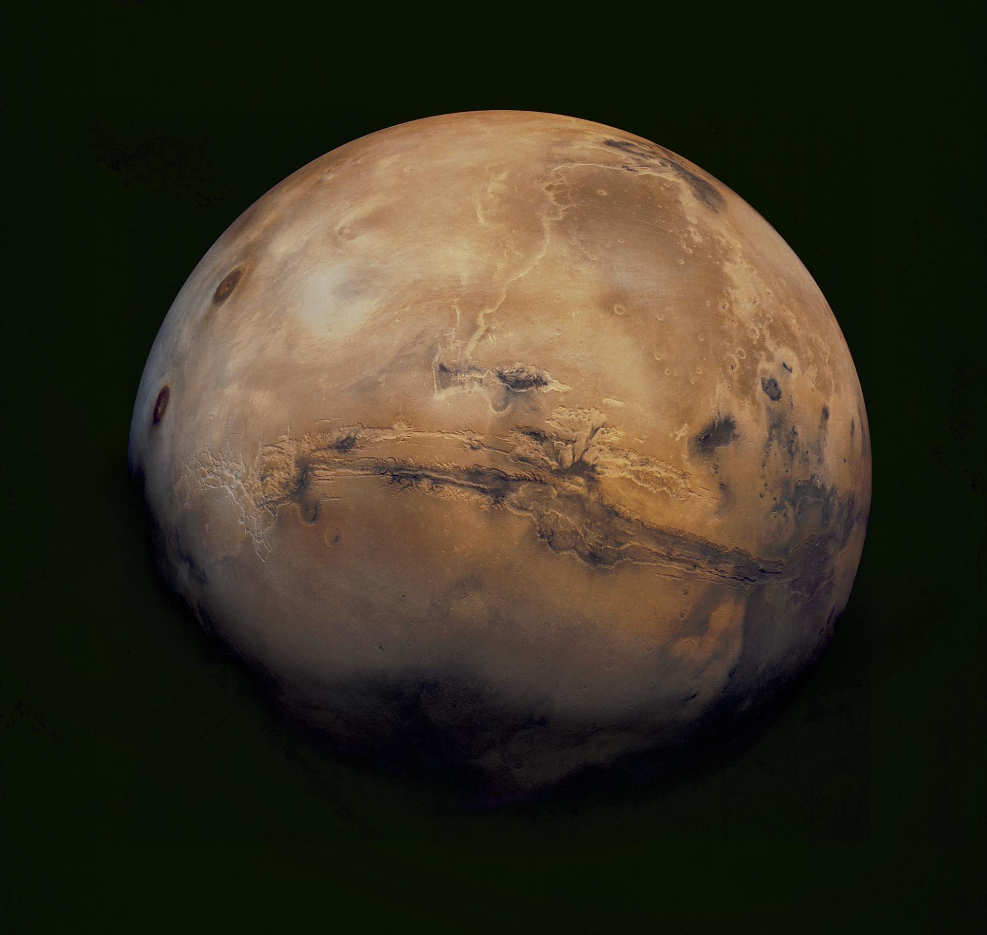 A view of Mars showing a large crater across the middle of the red planet.