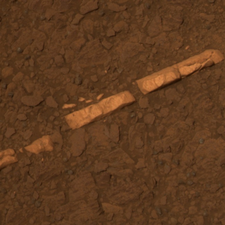 A light mineral vein is revealed in rectangular chunks in the Martian dirt.