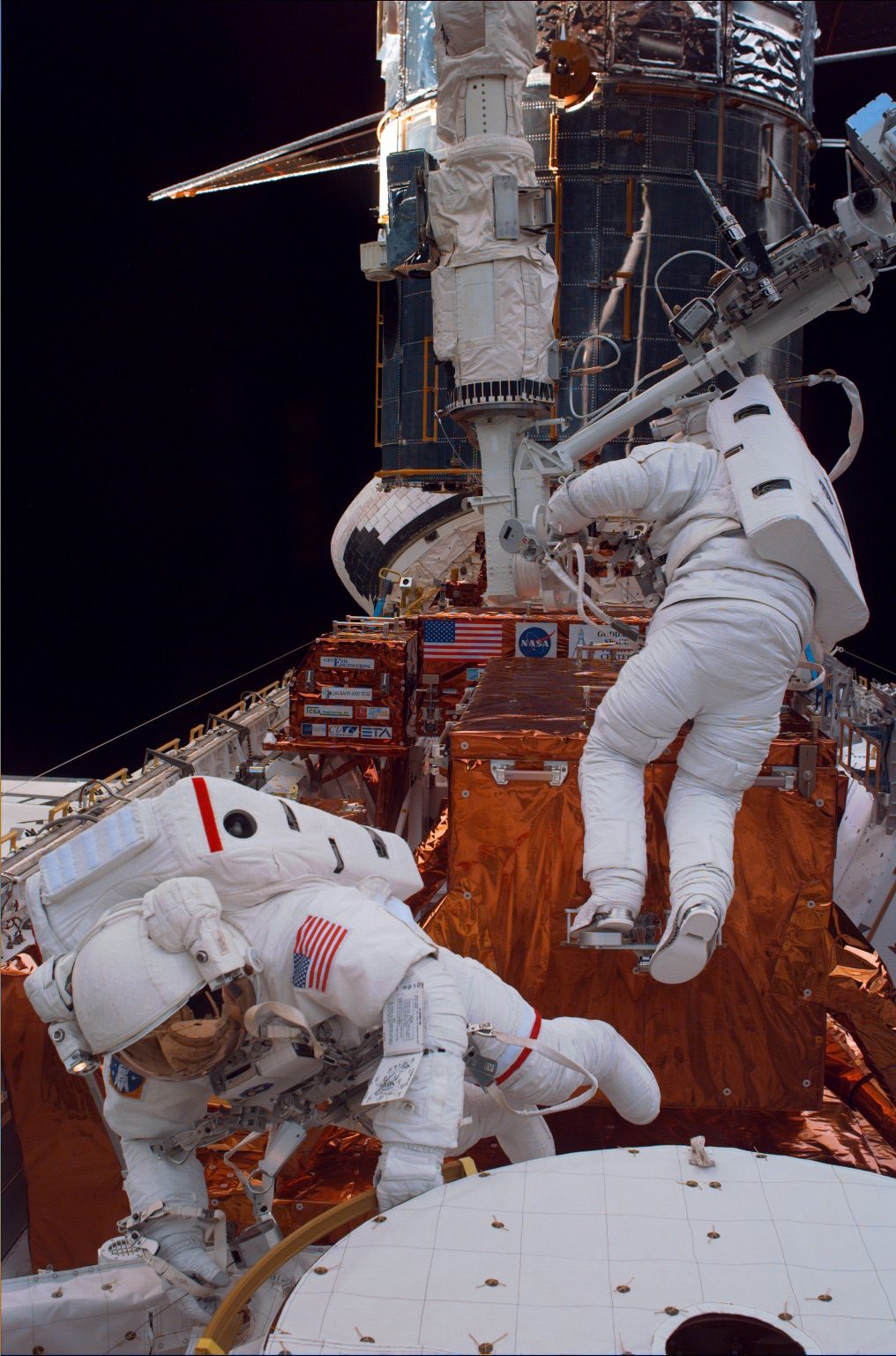 Two astronauts work on Hubble in the space shuttle's cargo bay.
