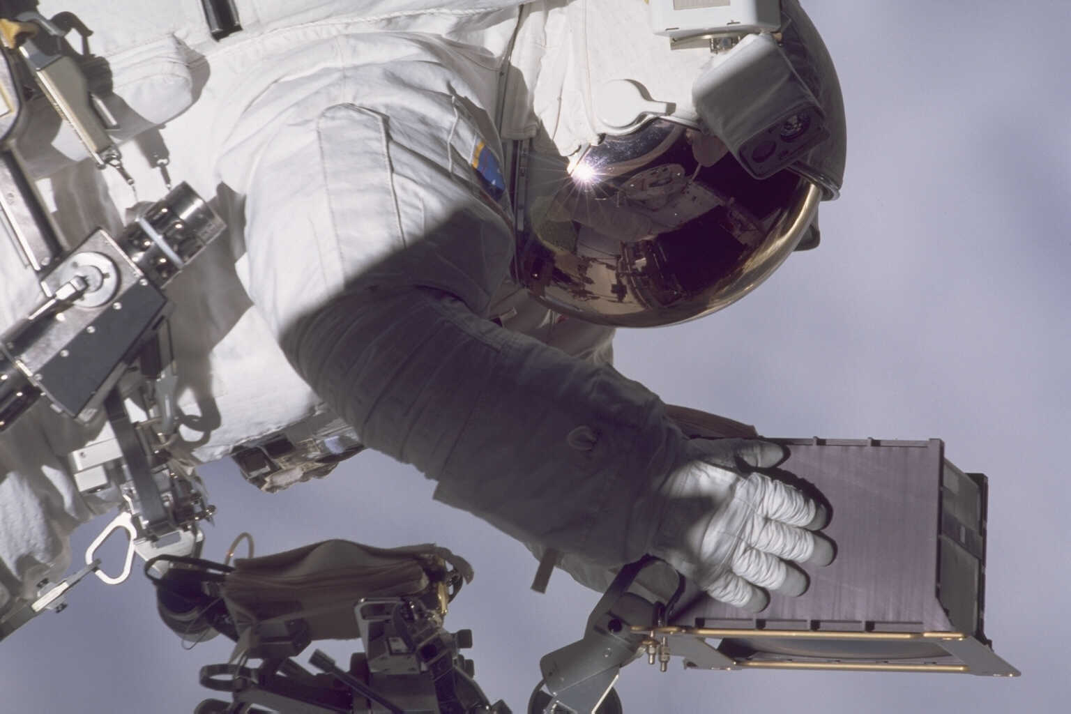 Astronaut John Grunsfeld is maneuvering over to the Hubble spacecraft with a box to install