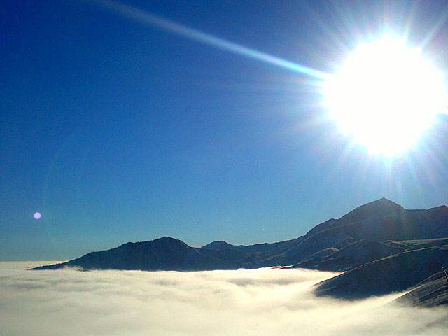 Sun shining brightly over misty mountains.