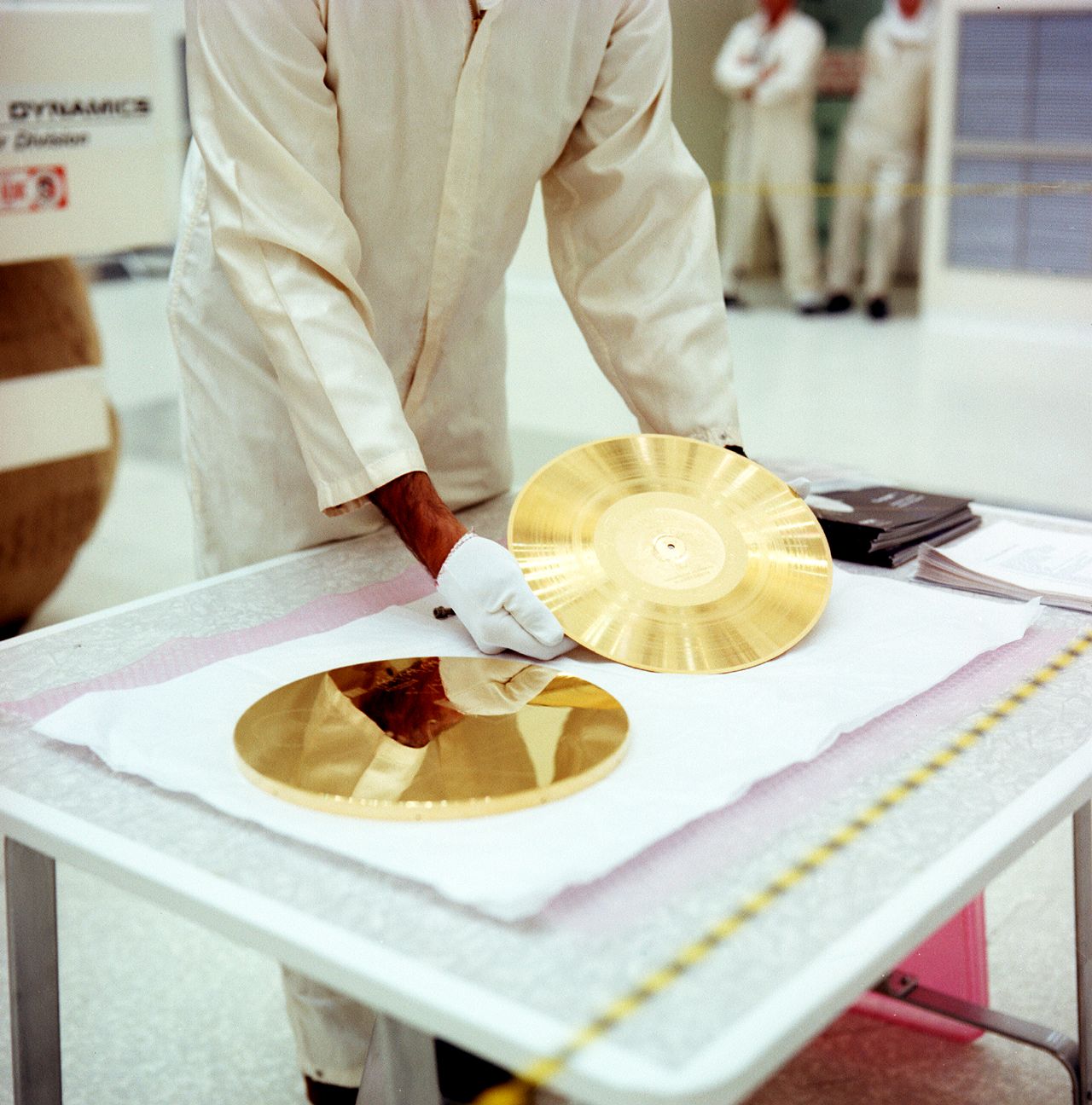 A man carefully places the golden record next to its cover in a NASA cleanroom.