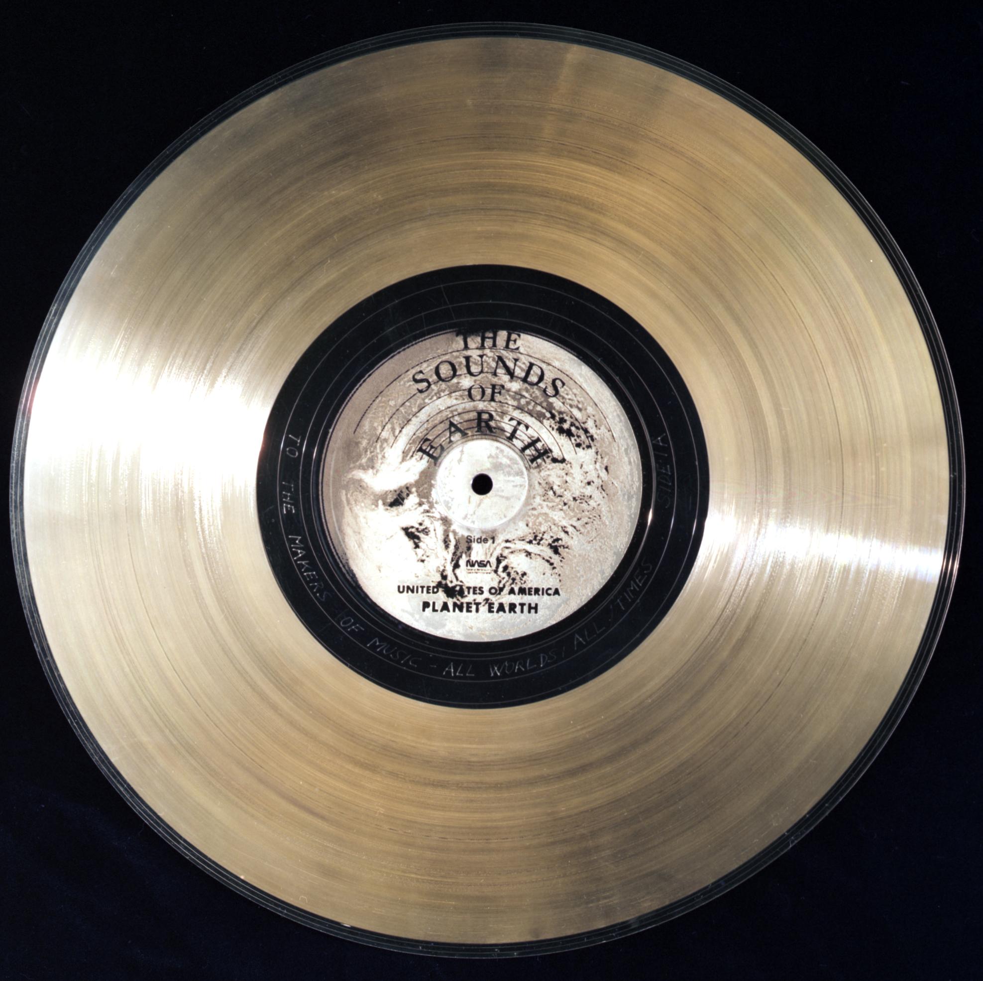 A golden record album with The Sounds of Earth United States of America, Planet Earth and etched with "To the makers of music, all worlds, all time."