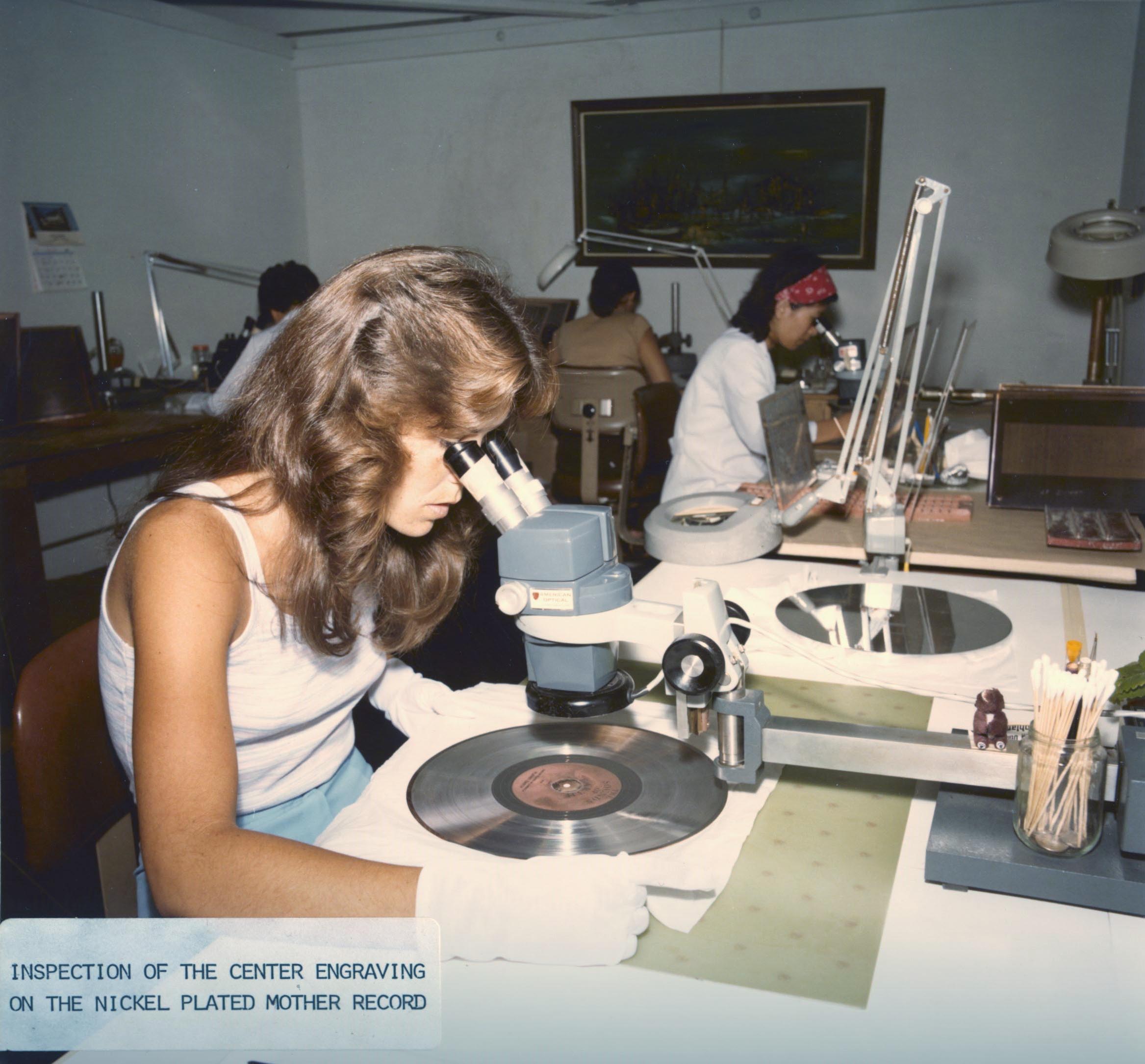 A woman inspects the Voyager Golden Record with a microscope.