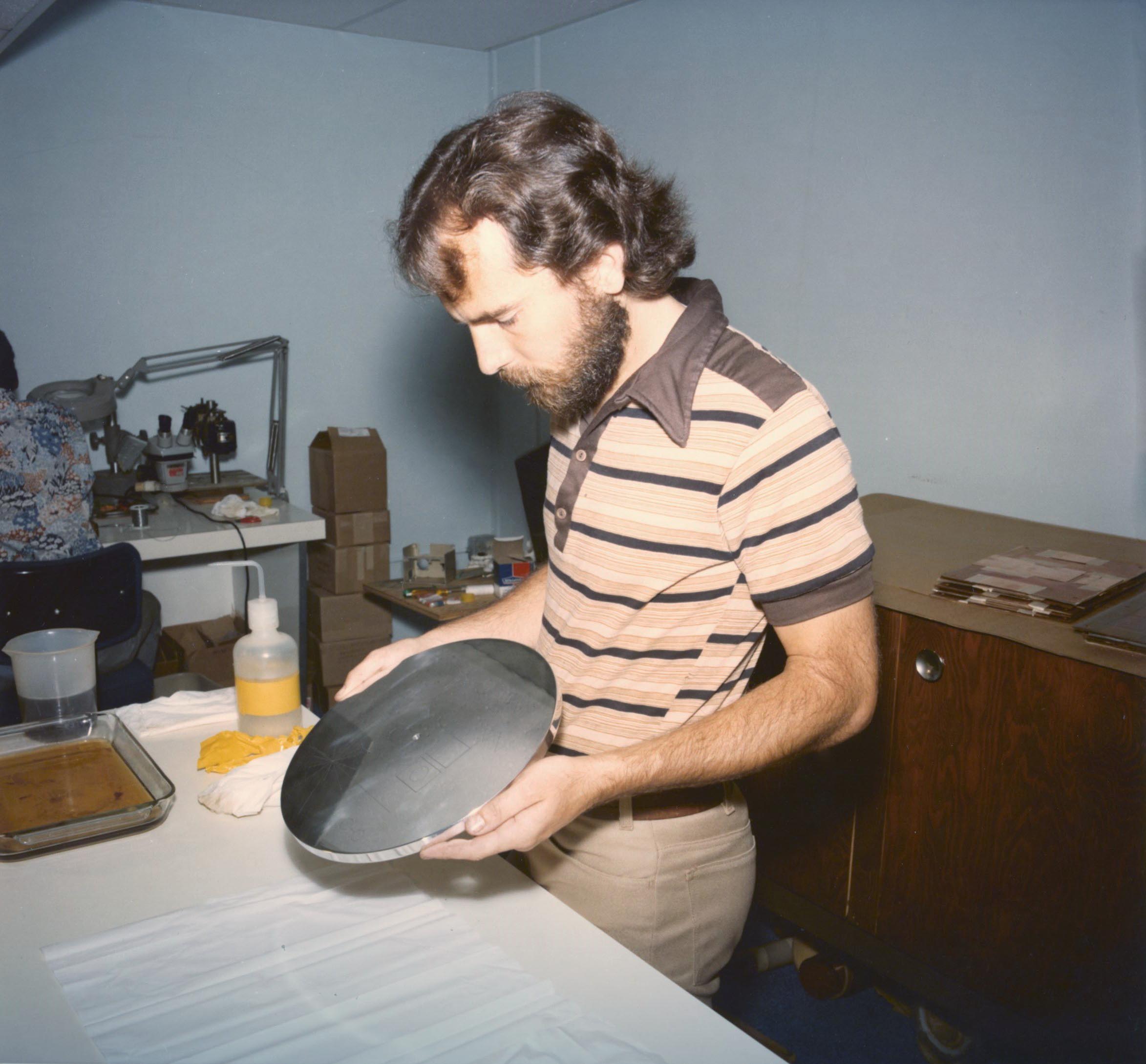 A man examines a polished album-sized disc.