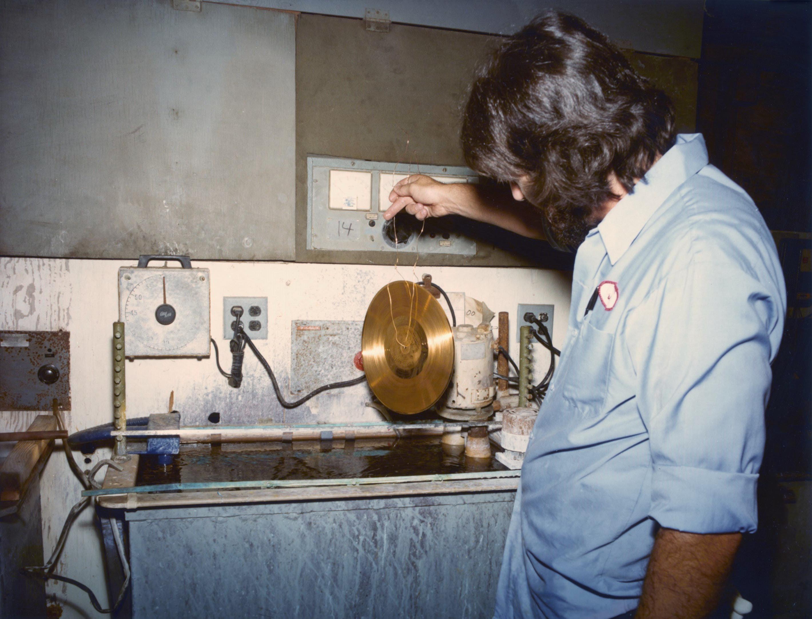 A man lifts the Voyager Golden Record from a sink-sized chemical vat.