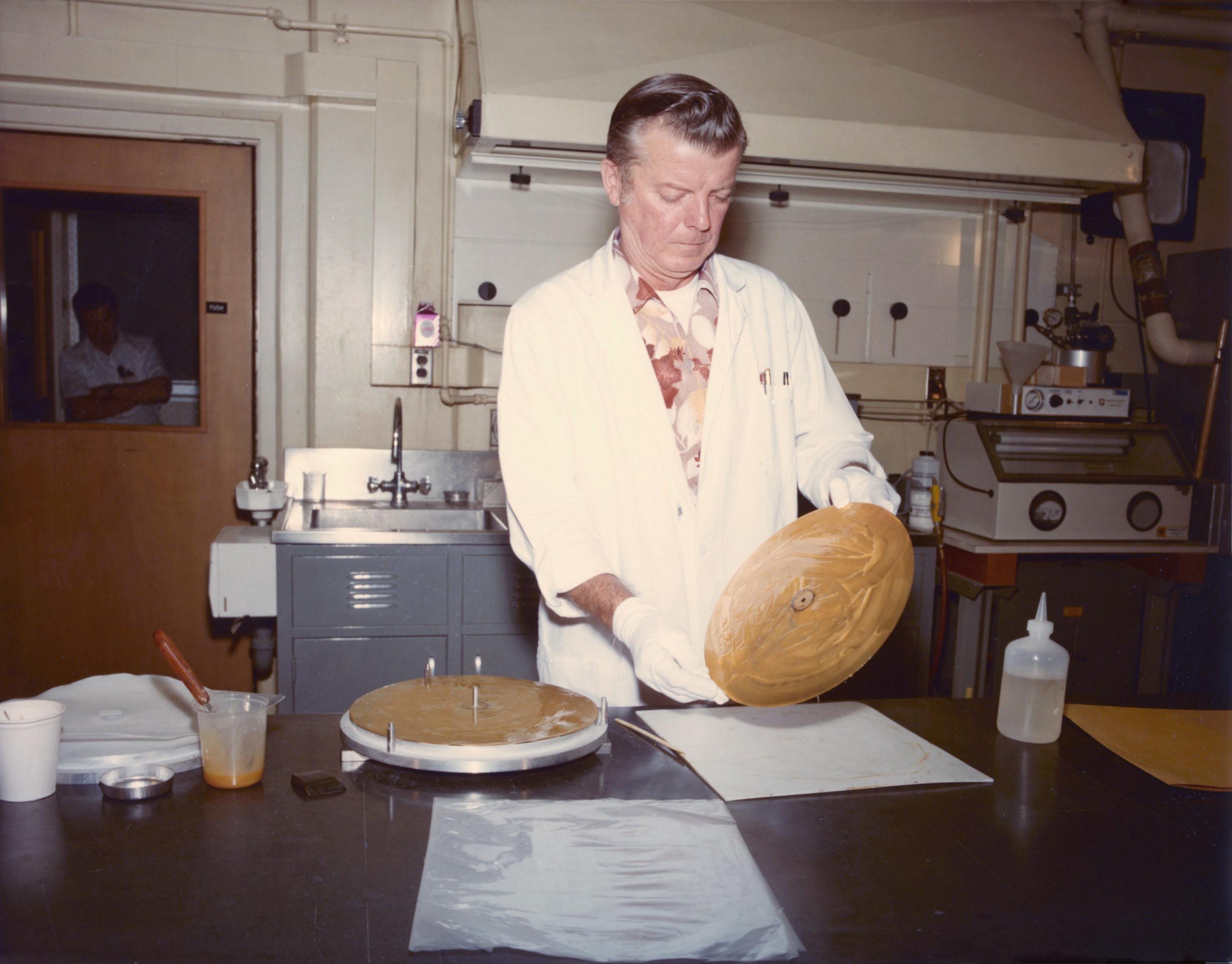 A man in a lab holds up the Voyager Golden Record.