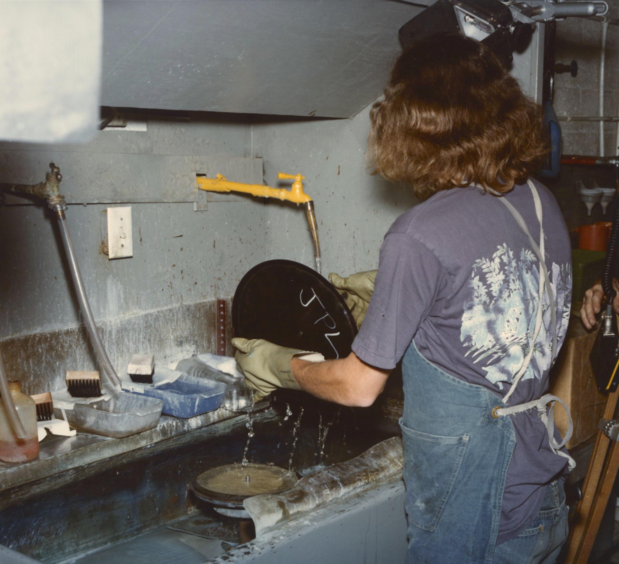 A person rinses off a record disc marked JPL.