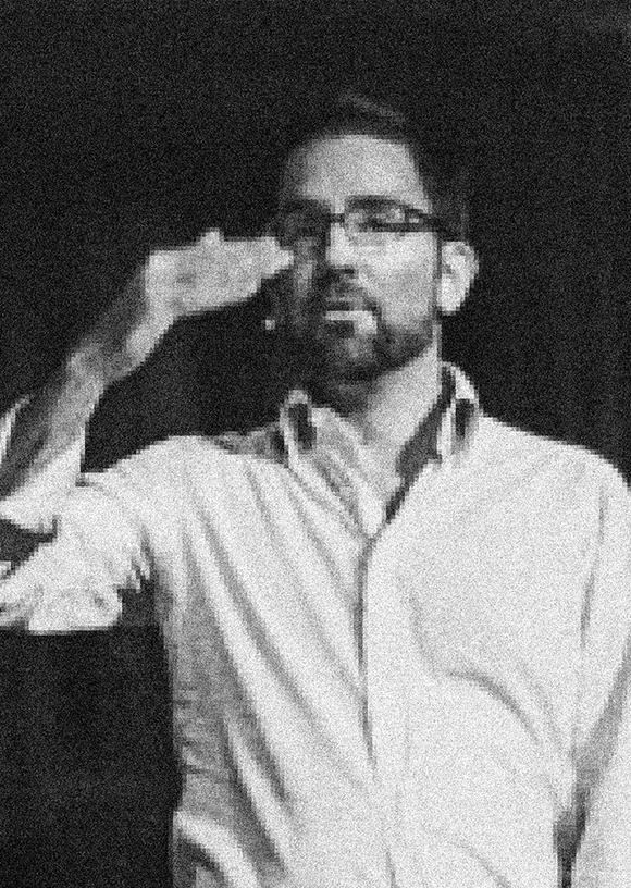 John W. Conklin headshot while speaking, male, black and white photo, glasses, beard, button down shirt.