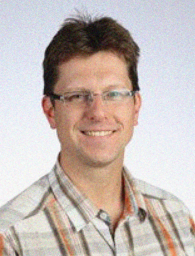 Brian Fleming headshot, male, brown hair, glasses, plaid button-down shirt, smile.