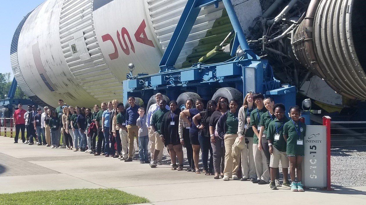 Photo of participants at the 2024 U.S. GLOBE Southeast Student Research Symposium standing in front of the Apollo Saturn V rocket.