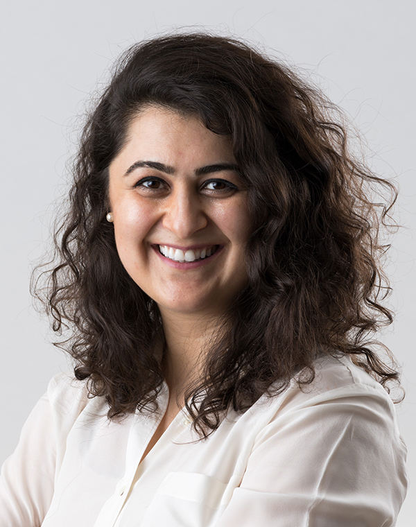 Sona Hosseini headshot, female, brown wavy hair, white shirt, smile.