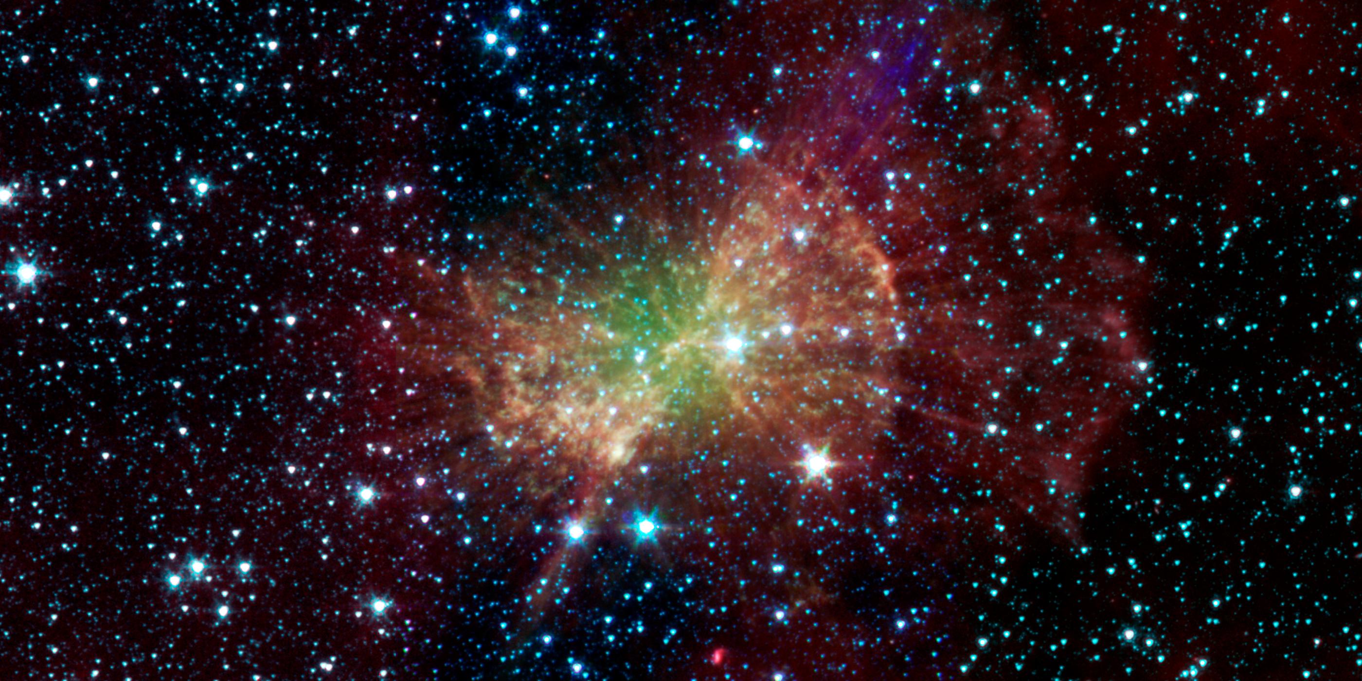 The Dumbbell Nebula pumps out infrared light in this image from NASA's Spitzer Space Telescope with green in the center, orange in the middle and red on the outer layer.