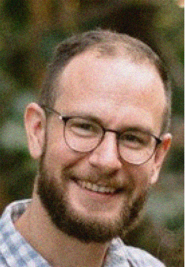 Adam McCaughan headshot, male, light brown hair, beard, glasses, smile.