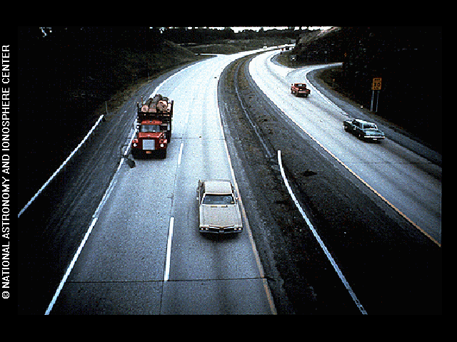 A modern highway with two lanes in each direction and two cars on each side