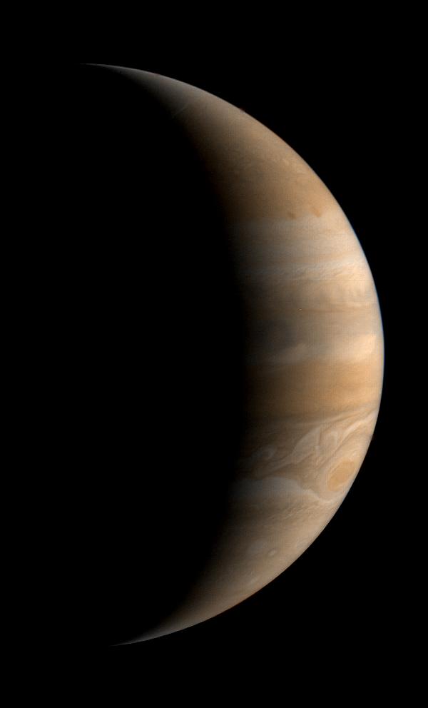 Jupiter looks serene with only a thin crescent illuminated by the Sun.