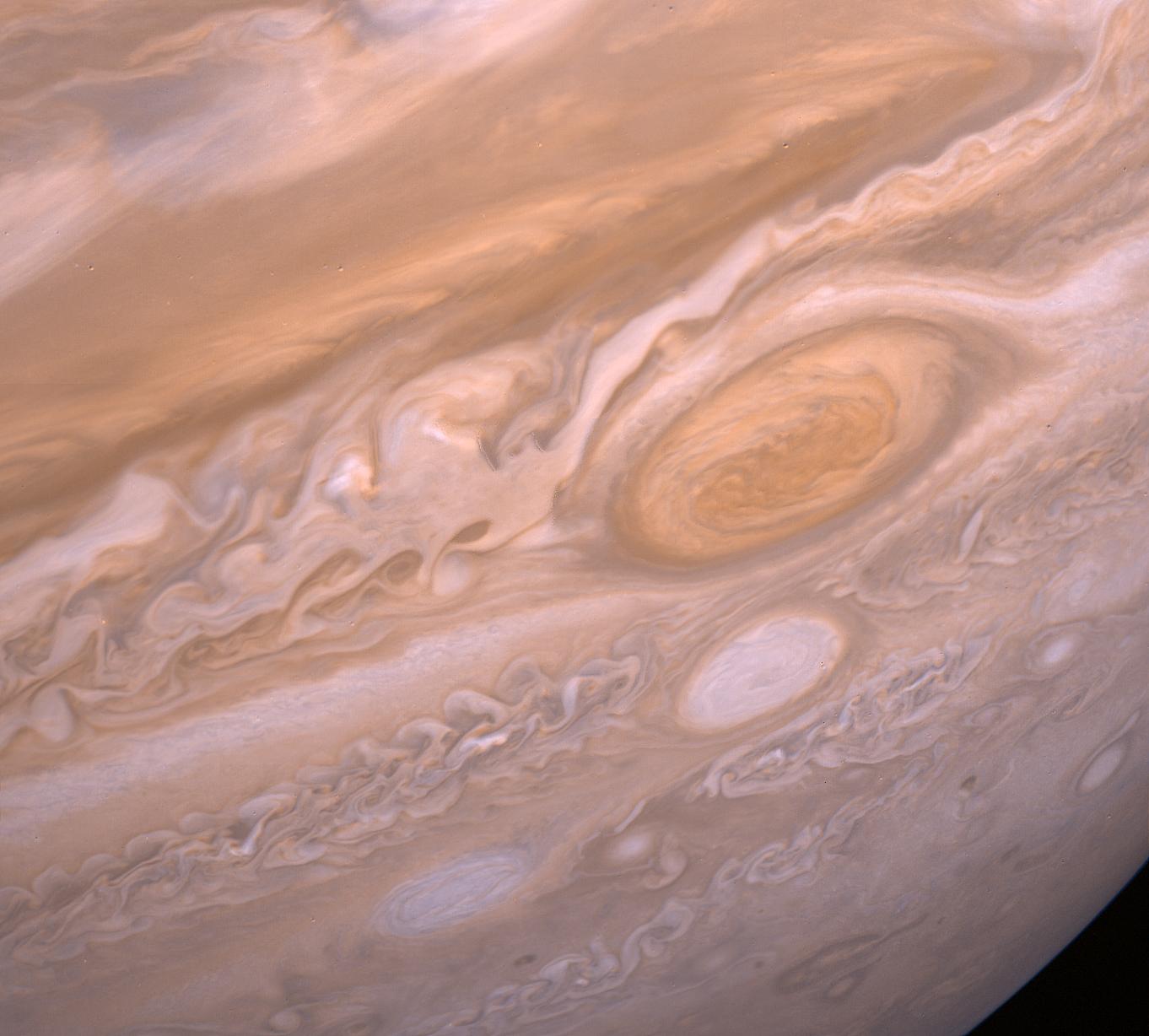 A close up of swirling clouds and oval storms, including the giant Great Red Spot, on the face of Jupiter.