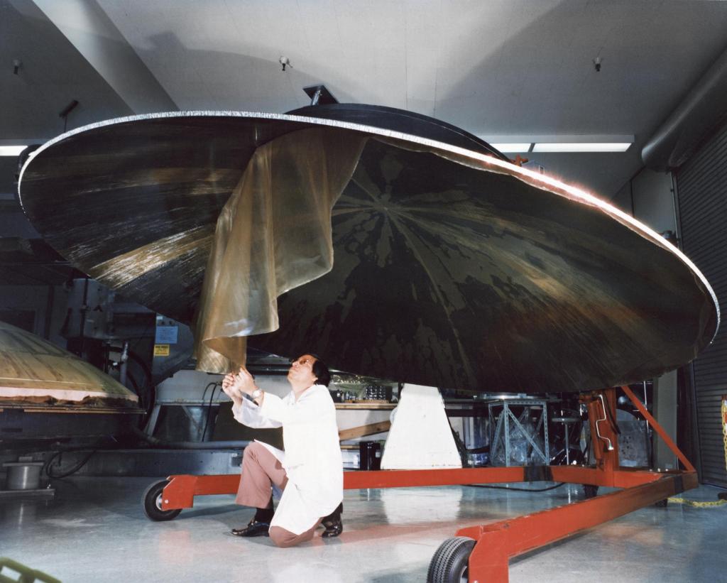 A man removed protective wrap from a large antenna dish.