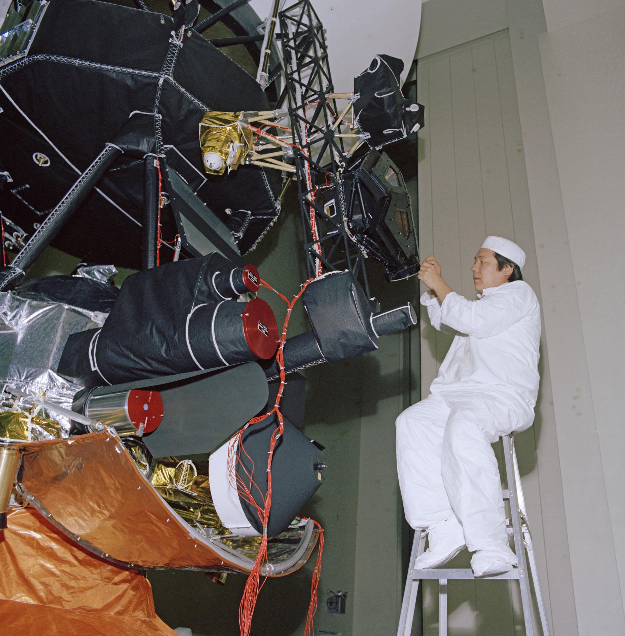 An engineer works on vibration acoustics and pyro shock testing for one of NASA's Voyager spacecraft. Several of the spacecraft's science instruments are visible at left.