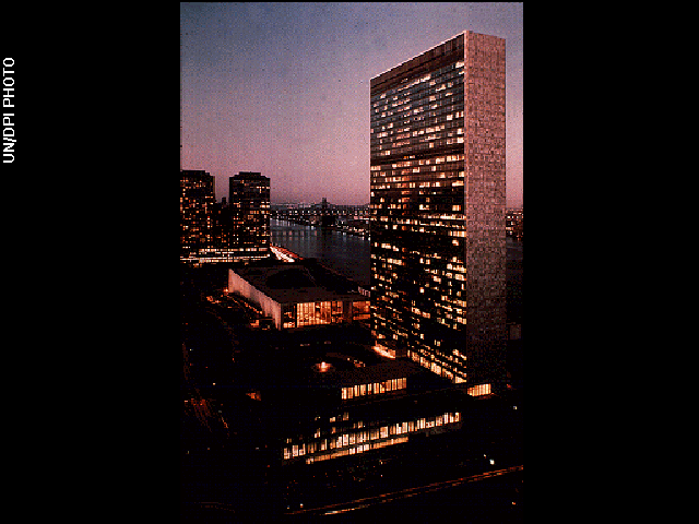 The United Nations building, a tall structure, photographed at night with lights illuminating its windows