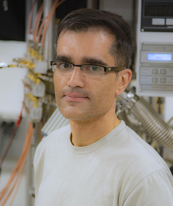 Varun Verma headshot, male, dark brown hair, glasses, white shirt.