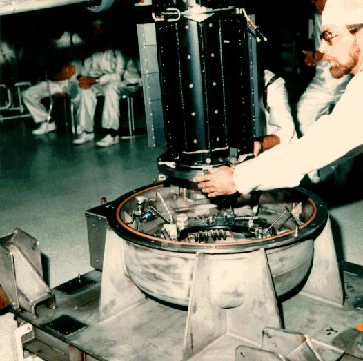 A man in a cleanroom lowers a test model into a sturdy shipping container.