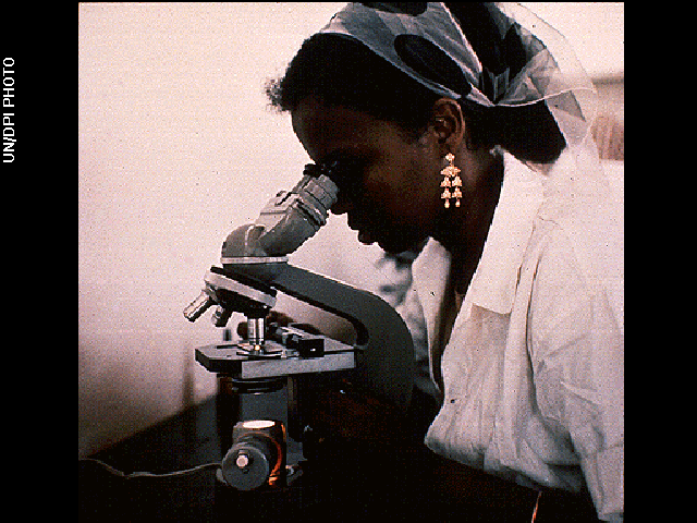 A woman looking through the eyepiece of a microscope