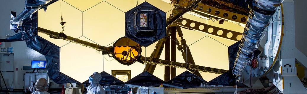 Technicians and engineers visually inspect the support structure of the James Webb Space Telescope that holds it in place.