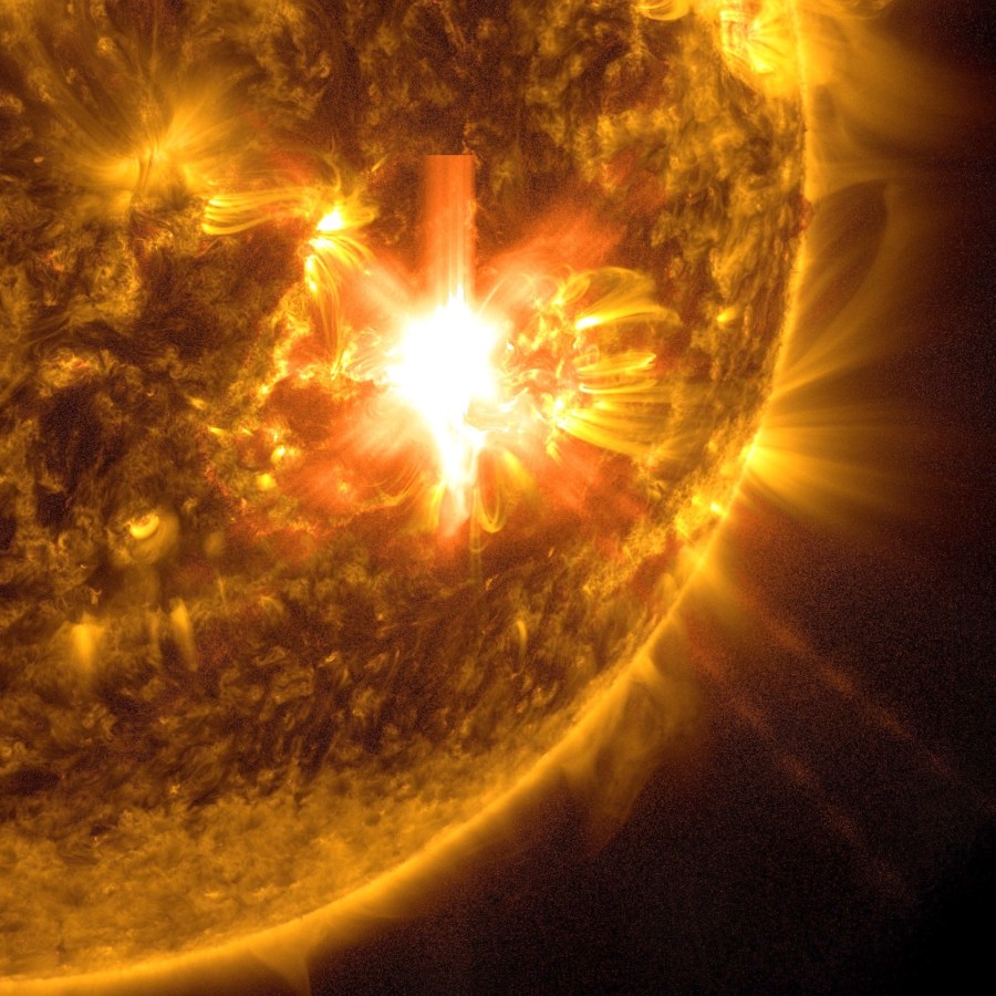 The bottom right area of the Sun, shown in gold and against a black background. There are some loops cascading off the Sun. Toward the middle is a bright white area â the solar flare.