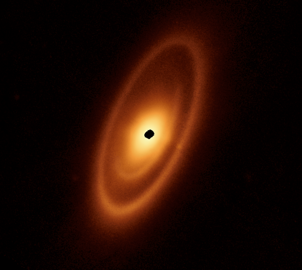 An orange oval extends from the 7 o’clock to 1 o’clock positions. It features a prominent outer ring, a darker gap, an intermediate ring, a narrower dark gap, and a bright inner disk. At the center is a ragged black spot indicating a lack of data.