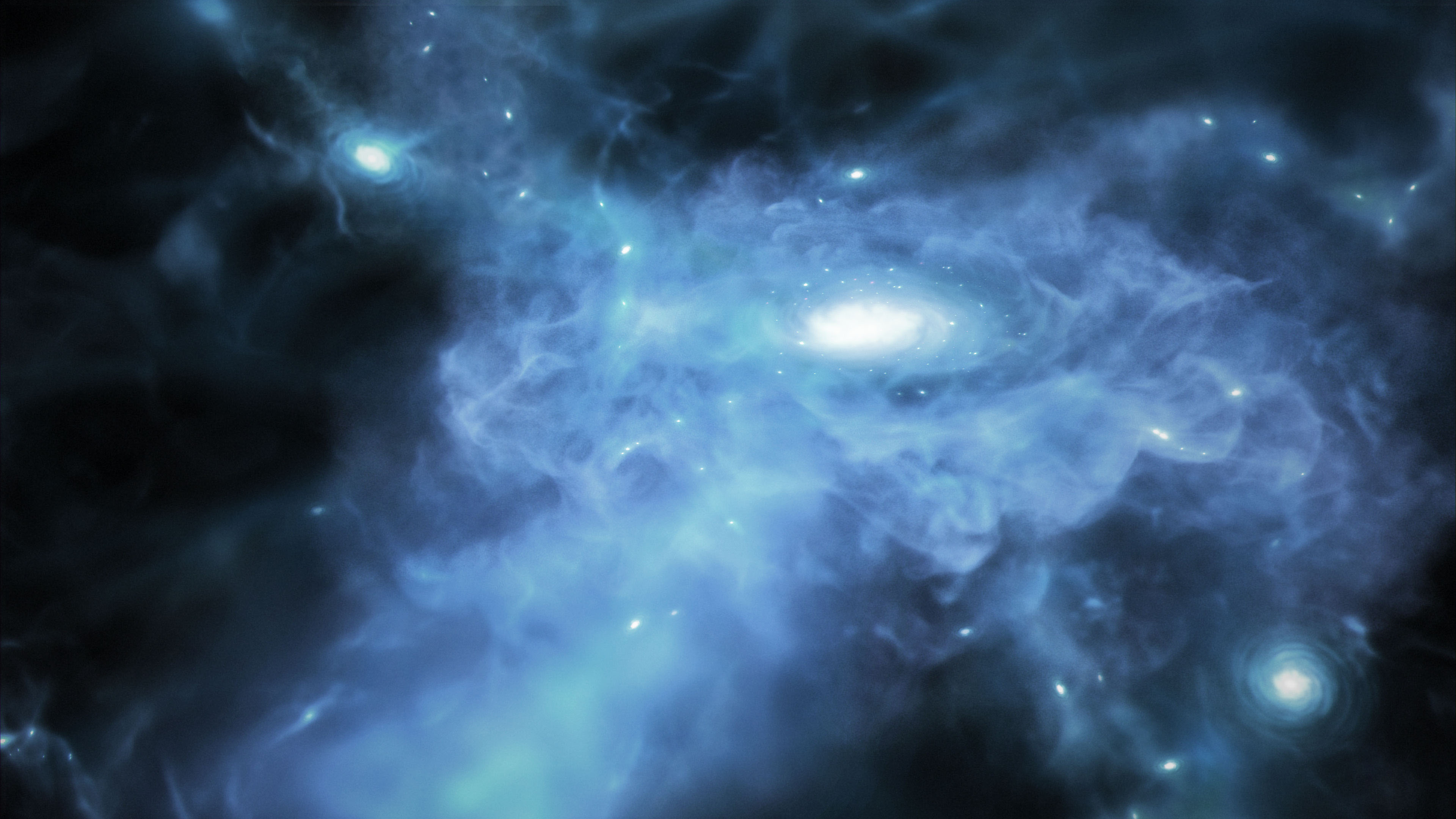 This illustration is awash in bright blues, with only areas of the black background of space peeking out near the edges. Just above center is a large white spiral galaxy that is forming within a large cloud of blue gas. Its spiral arms twirl clockwise. Immediately around the galaxy’s edges are larger light blue dots. The gas appears thicker and brighter blue below the galaxy and toward the bottom left in what looks like a loose, extended column. Other wispy blue gas appears all around the galaxy, extending to every edge of the illustration. There are two additional spiral galaxies, though they are about half the size of the one at the center. They appear toward the top left and bottom right, and both are connected to regions of blue gas. Several bright knots dot the brightest blue areas near the center, and toward the top right. The background is clearer and more obviously black along a wider area at the left edge, a sliver along the top right, and in triangles toward the bottom right corner.