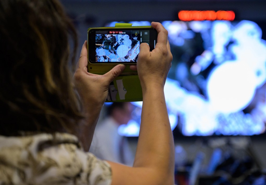 A person's arms can be seen holding a smartphone to record something.