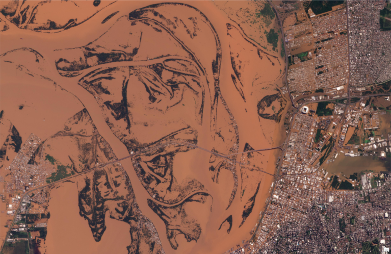 satellite image showing brown-hued and flooded waterway near urban area