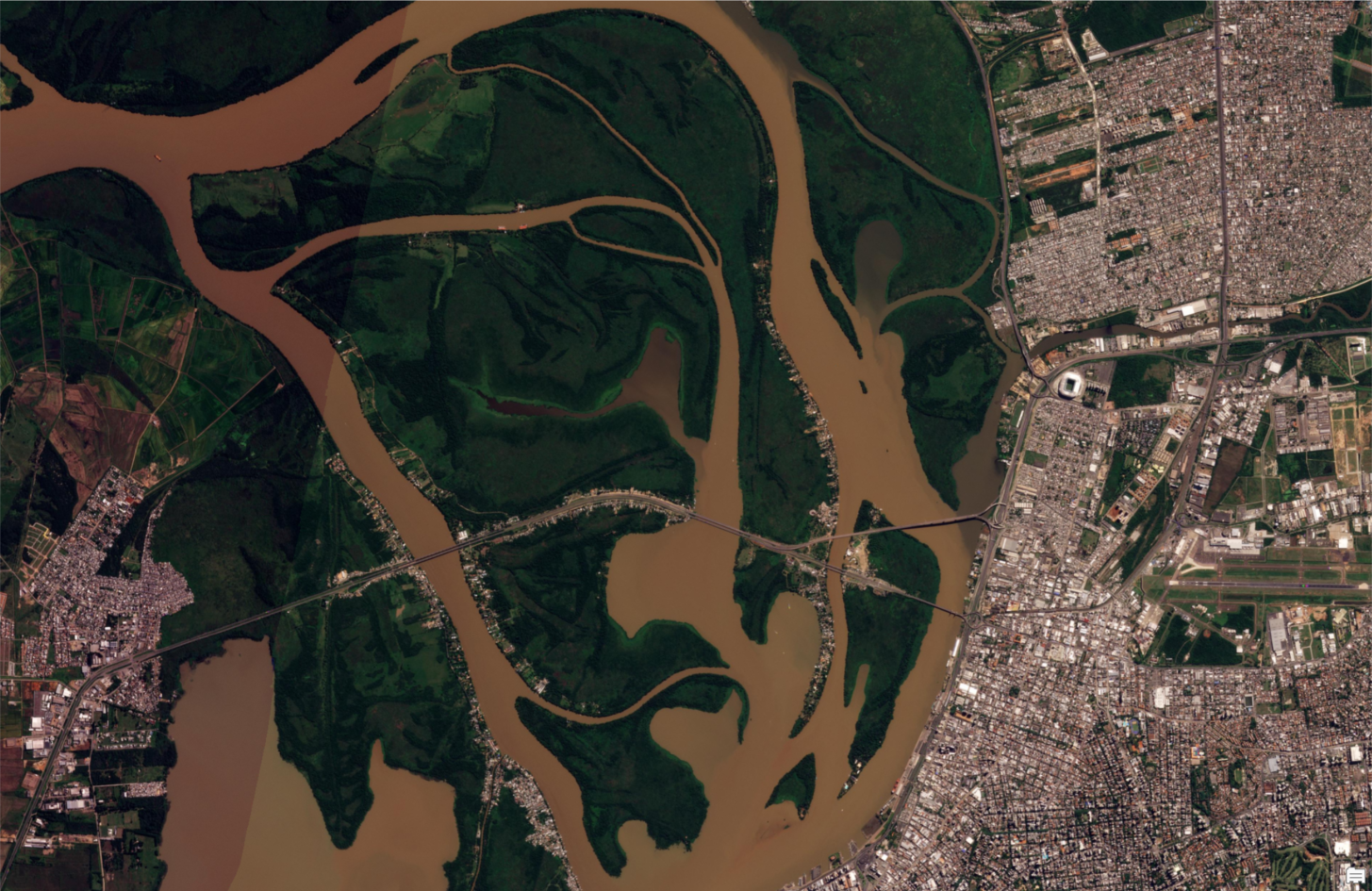 satellite view of a brown-hued waterway near an urban area