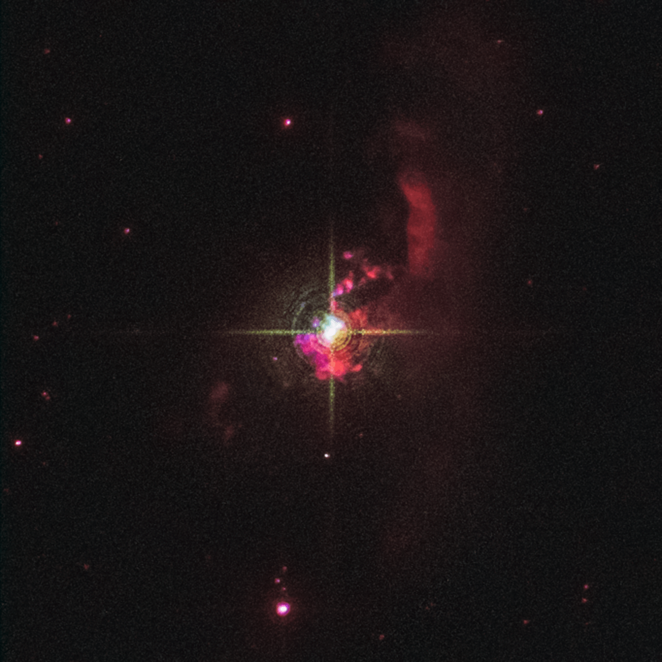 At the center of the image is a bright white star with four prominent diffraction spikes. The star is surrounded by clumpy red nebulosity. A more translucent, red finger-shaped cloud of material points upward to the star's upper right. Hubble Space The black background of space is sprinkled with tiny red and white stars.