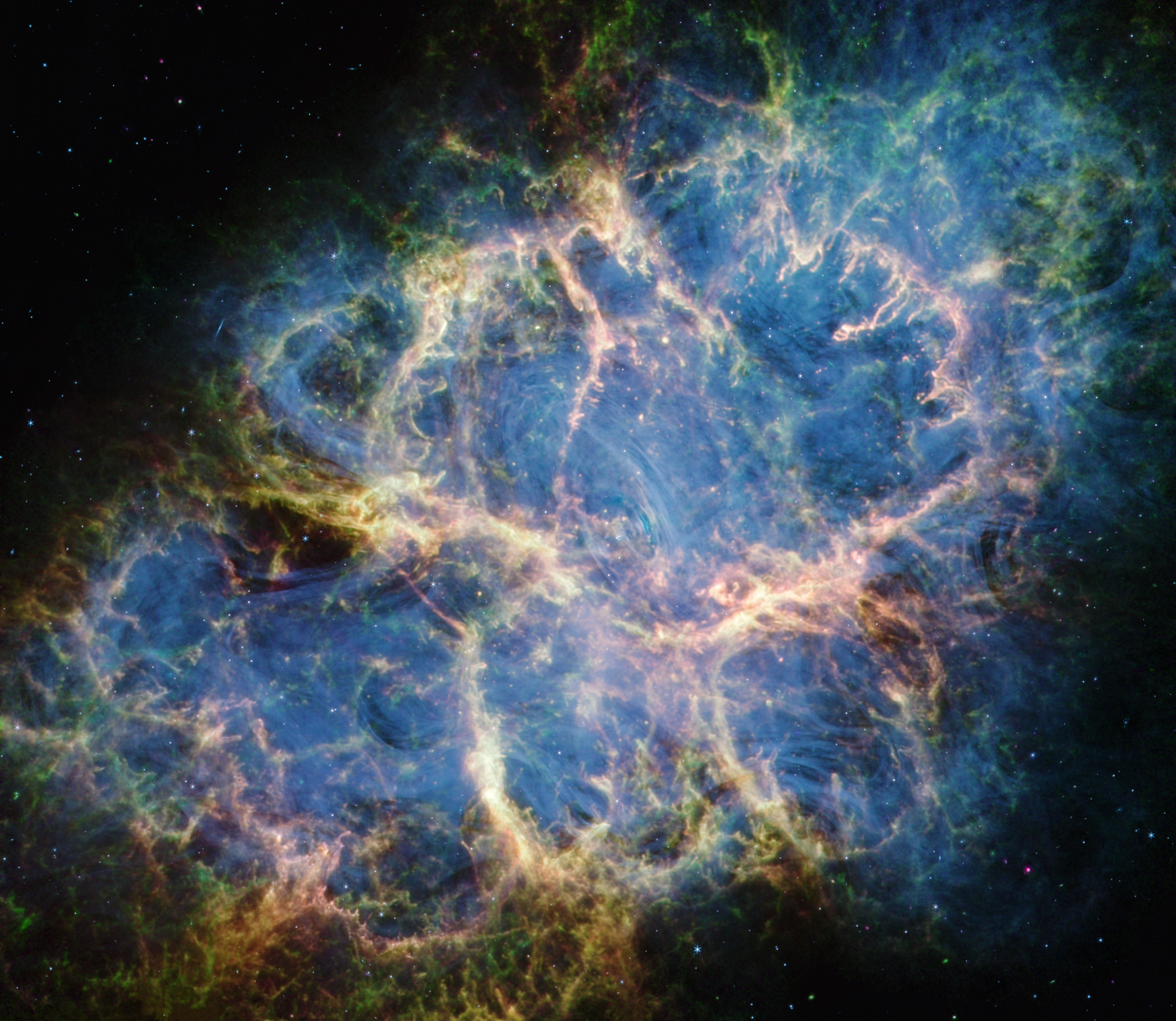 The Crab Nebula. An oval with complex structure extends from lower left to upper right against a black background. On the oval's exterior lie curtains of glowing yellow and green fluffy material. Its interior shell shows large-scale loops of mottled filaments of yellow-white and green, studded with clumps and knots. Translucent thin ribbons of smoky blue lie within the remnant's interior, brightest toward its center. The blue material follows different directions throughout, including sometimes sharply curving away from certain regions within the remnant. A faint, wispy ring of blue material encircles the very center of the nebula. Around and within the supernova remnant are many points of blue, green, purple, and white light.