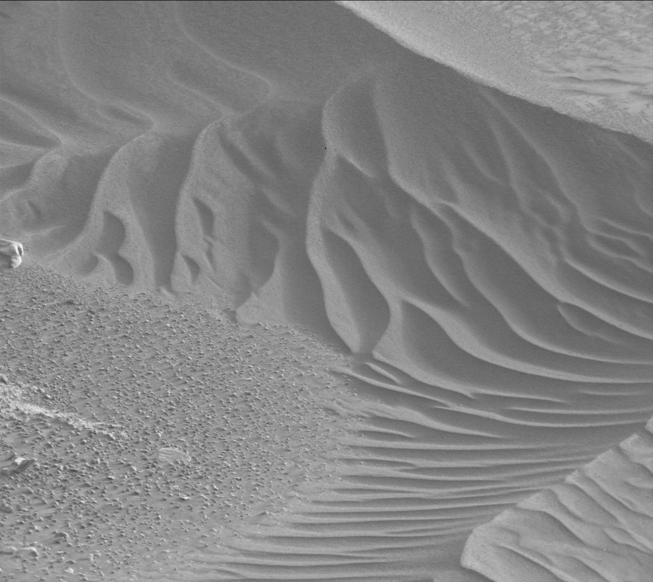A black and white photo of a Martian landscape, looking cross-hatched as if viewed through a window screen. The terrain at lower left resembles coarse sandpaper, while the other three-quarers of the image frame show undulating dunes, looking like folds in satin fabric.