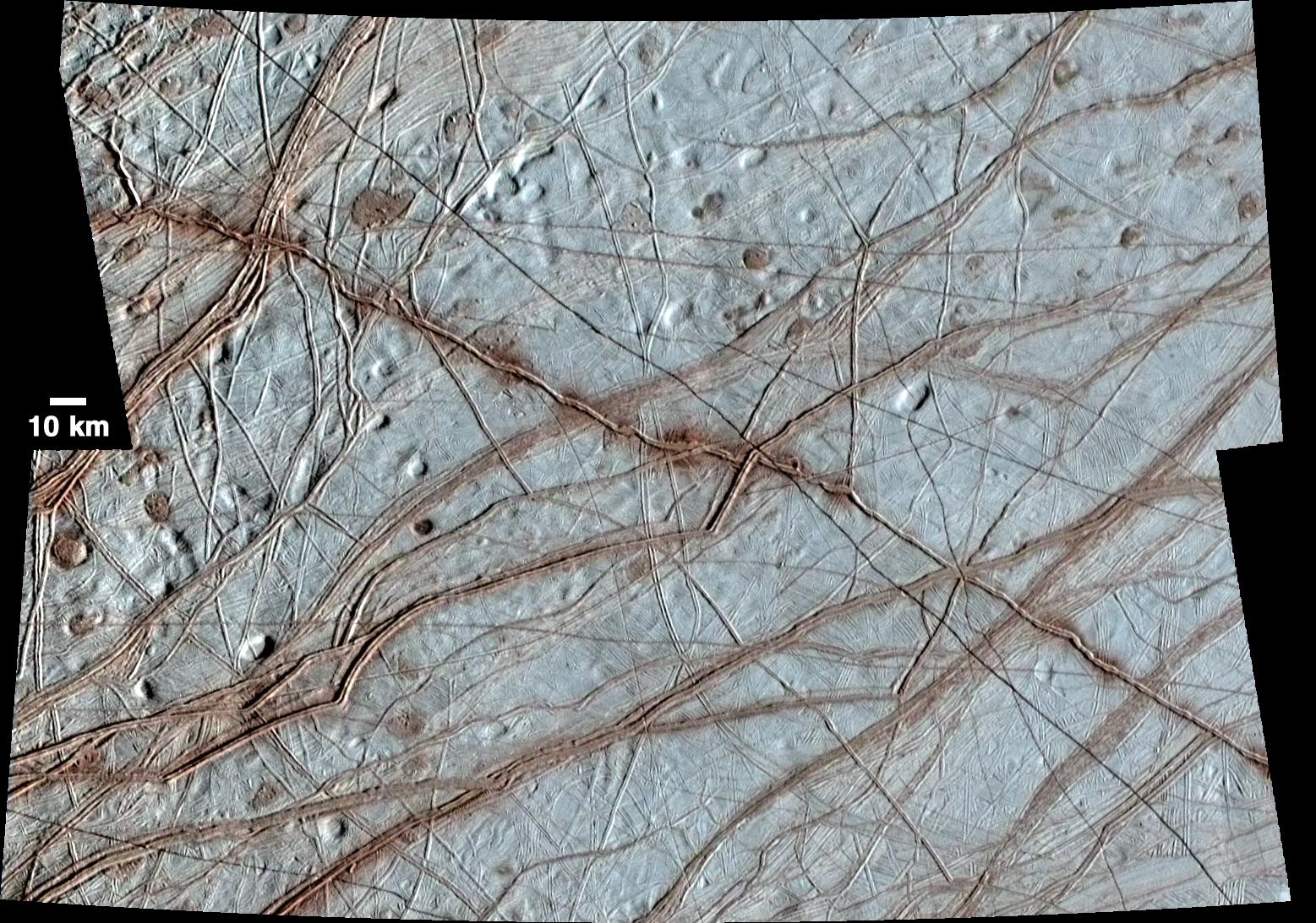 Many features on Europa's surface are visible in this close-up image including reddish lines criss crossing the cream-colored surface.