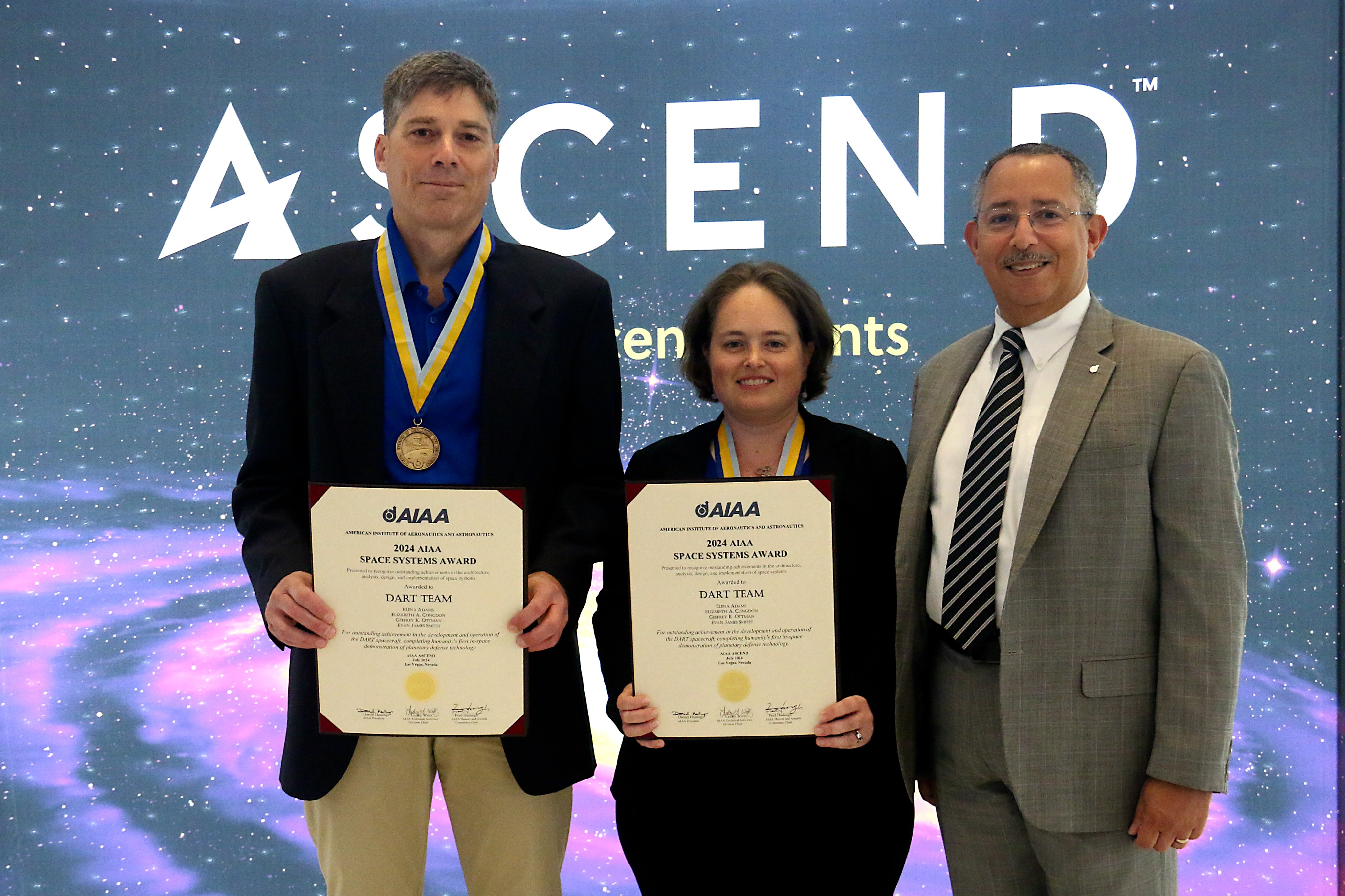 APL's Geffrey Ottman (left), electrical systems engineer on NASA’s DART (Double Asteroid Redirection Test) and APL's Betsy Congdon (center), who served as the mechanical systems engineer on the mission, accepted the 2024 American Institute of Aeronautics and Astronautics (AIAA) Space Systems Award