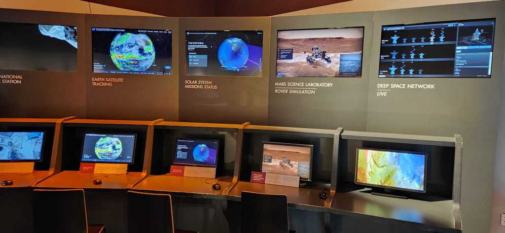 A bank of monitors showing various NASA Eyes interactives for visitors to experience.