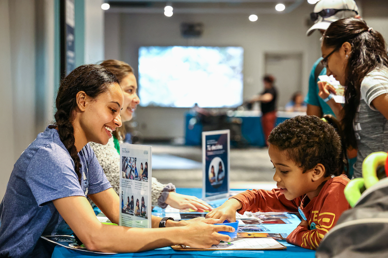 Educators and a family do a hands-on activity together at a science center.