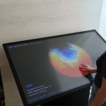 A woman interacts with an Eyes on Earth exhibit touch table.