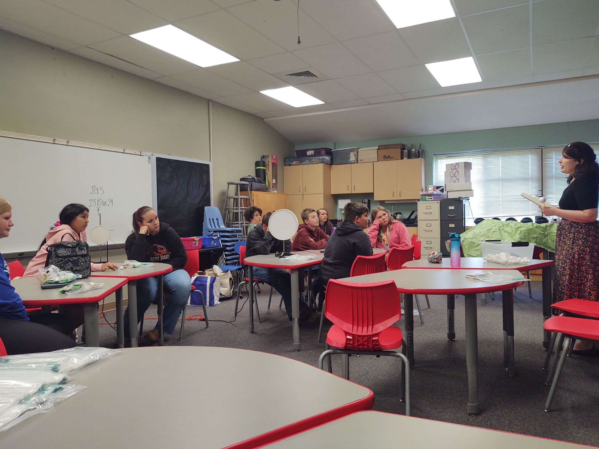 Nine students in a classroom (left) listening to Dr. Alissa Bans (right).