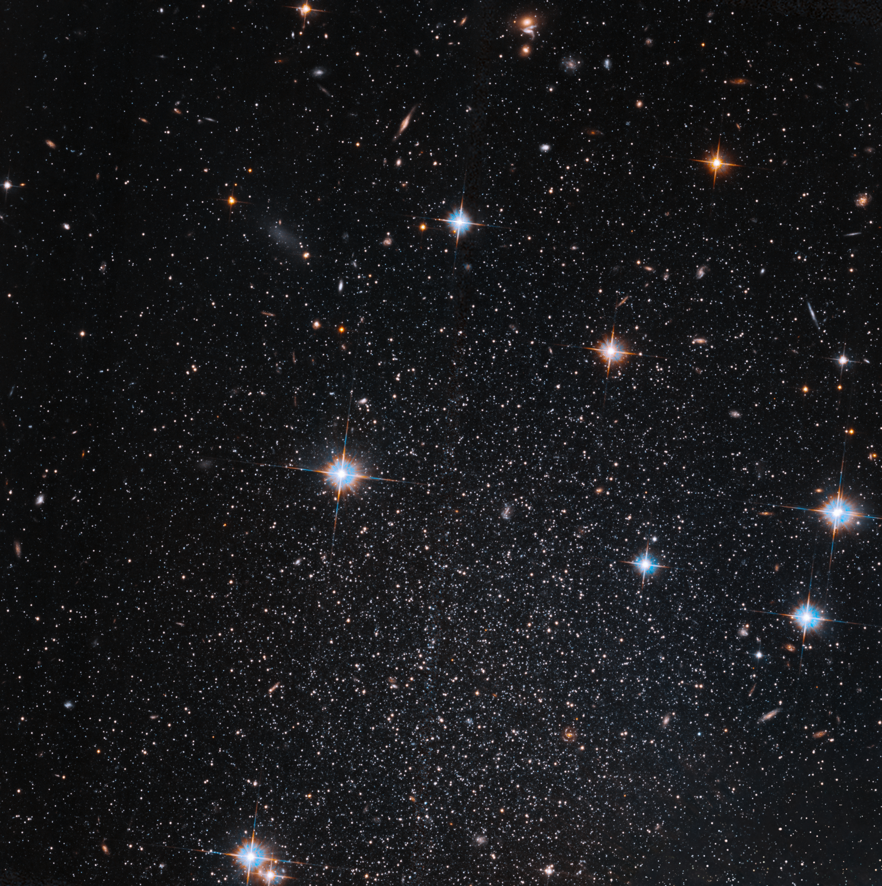 Several stars shine against black space. A few foreground stars with diffraction spikes throughout.