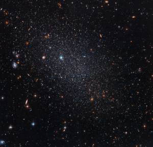 More closely concentrated near the center, several stars shine against black space along with a few distant galaxies.