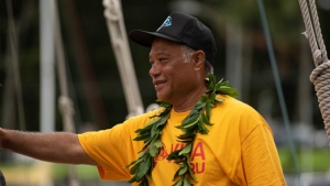 A man in a yellow shirt and a black hat on a boat.